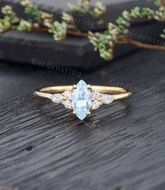 an aqua blue topazte and diamond ring on a wooden surface with flowers in the background