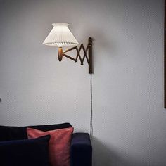 a living room with a blue couch and a white lamp on the wall next to it