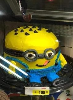 a yellow and blue cake sitting on top of a black plate in a display case