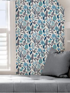 a blue and white floral print curtain hanging on a wall next to a gray couch