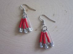 two pairs of red beads hanging from silver earwires on a wooden table top