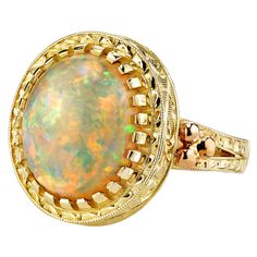 The 4.30 carat opal in this handmade 18k yellow gold ring is bursting with color! This gemstone displays flashes of bright green, orange, yellow, and the most highly-prized and rare color: red! It is difficult for photos to do this opal justice. This ring was custom-designed by our Master Jewelers in Los Angeles in order to showcase the high dome, depth of color and life in this gem. The sides of the ring have been hand engraved and show a level of artisanship and skill seldom seen today. A ring like this requires untold hours to bring to life, but will be enjoyed and treasured for years! Size 7 Complimentary sizing as needed Gem Ring, 18k Yellow Gold Ring, Domed Ring, Yellow Gold Ring, Gems Jewelry, Hand Engraving, Gold Gold, Bright Green, Green Orange