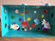 an open box with fish and sea creatures hanging from it's sides in front of a colorful wall