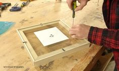 a person cutting out a piece of paper on top of a wooden table with scissors