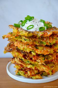 a stack of vegetable fritters with sour cream on top