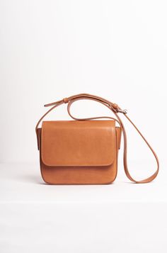 The Palmar is a leather crossbody bag that features a roomy compartment, a slim interior pocket, and one exterior pocket. It is handmade from vegetable-tanned leather and has a front flap closure with a magnetic snap. The leather strap can be adjusted to suit your preferred length, and the bag has a beige cotton lining. The exterior pocket allows you to keep your wallet and phone handy, yet safe at the same time. The sides and edges of the leather are delicately painted. This bag is joyfully man Everyday Saddle Flap Bag With Adjustable Strap, Everyday Use Saddle Flap Bag With Adjustable Strap, Everyday Saddle Bag With Detachable Strap, Everyday Cognac Shoulder Bag With Detachable Strap, Classic Saddle Shoulder Bag For Everyday, Daily Use Saddle Bag With Adjustable Strap, Everyday Cognac Flap Bag With Detachable Strap, Classic Crossbody Shoulder Bag With Removable Pouch, Classic Flap Bag With Detachable Strap For Daily Use