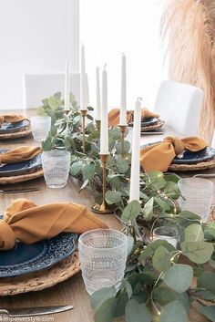 the table is set with candles, plates and place settings for an elegant thanksgiving dinner