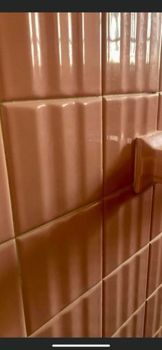 the corner of a bathroom with brown tiles and a white toilet paper dispenser