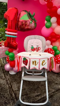 a baby's high chair and table set up for a strawberry themed birthday party