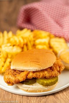 chicken sandwich with pickles and french fries on a plate