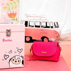 a pink purse sitting next to a white vw bus on a pink surface with flowers