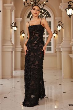 a woman in a black dress standing on a tile floor with chandelier above her head