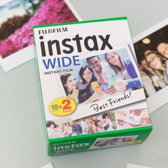 the fuji instax wide instant film is on top of some photos and cards