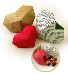 three origami heart shaped boxes next to each other on a white surface with a bowl full of candy