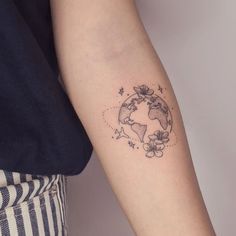 a woman's arm with a small earth tattoo on the left side of her arm