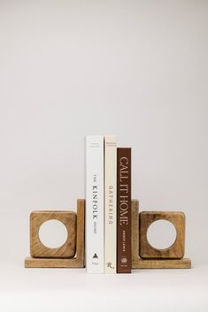 two books are stacked on top of each other in front of a bookend that is made out of wood