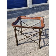 a table with a glass top sitting on the ground in front of a blue garage door