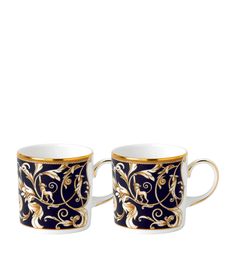 two black and gold coffee mugs sitting next to each other