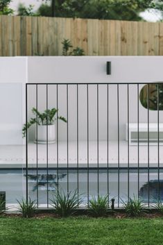 an outdoor swimming pool surrounded by grass and fenced in area with potted plants