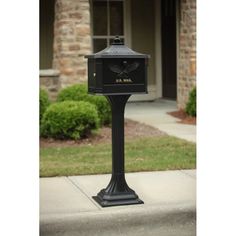 a black mailbox sitting on the side of a sidewalk next to a house and bushes