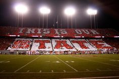 an empty football stadium with fans and banners on the bleachers at night time