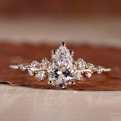 a close up view of a diamond ring on top of a wooden surface with leaves