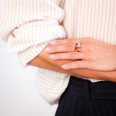 a woman's hand with a ring on her left wrist, wearing a white shirt and black pants