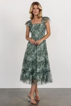 a woman in a green dress posing for the camera with her hands on her hips