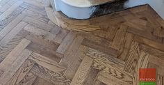 a cat sitting on top of a toilet in a bathroom next to a wooden floor