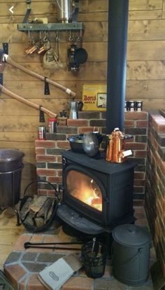 a wood burning stove sitting inside of a kitchen next to a brick wall with pots and pans on it