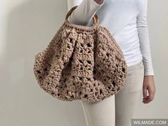 a woman is holding a crocheted purse