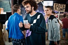 a group of young men standing next to each other holding signs and drinking beverages in their hands