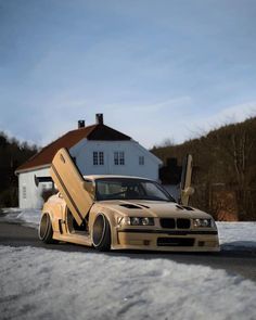 a car with its door open sitting in the snow next to a house and trees