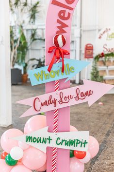 a pink sign with red and white balloons in the shape of candy canes on it