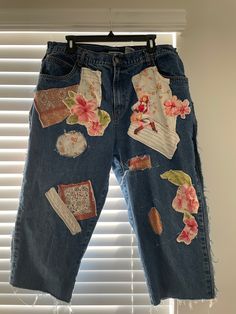 a pair of jeans with patches and flowers on them hanging from a window sill