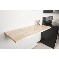 an empty kitchen with black appliances and wood counter tops on the counters, along with a wooden teddy bear