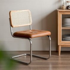 a brown leather chair sitting next to a wooden cabinet and glass case with dishes on it