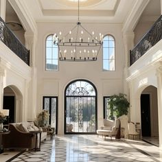 a large foyer with chandelier, chairs and couches in the middle of it