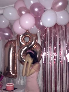 a woman standing in front of balloons with the number twenty eight on it's wall