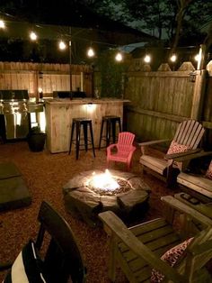 an outdoor fire pit surrounded by chairs and lights