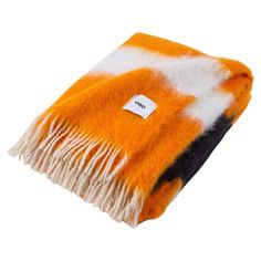 an orange, black and white blanket with a tag on it's end is shown