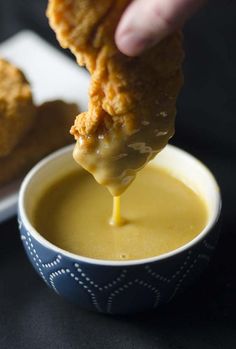 a person dipping some food into a bowl