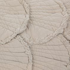 close up view of the texture of a quilted bed cover with fringes on it