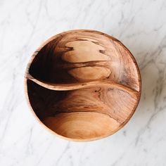 two wooden bowls sitting on top of a white marble countertop next to each other