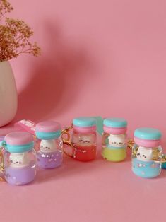 a group of small bottles with hello kitty in them sitting on a pink surface next to a potted plant