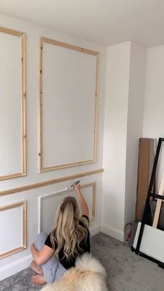 a woman is painting the wall in her living room with white paint and wood trim