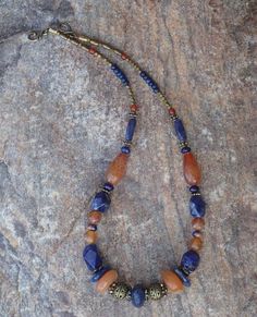 This necklace is subtle yet colorful.  Combines one large vintage African bead, two large vintage carnelian beads, orange sodalite beads, orange fire agate beads, and brass beads.  Also features a hook clasp.  The necklace is 17 inches long. Boho Jewelry Diy, Large Bead Necklace, Cowgirl Bling, Autumn Necklace, Beaded Jewelry Necklaces, Stone Beaded Necklace, Fire Agate, African Beads, Agate Necklace