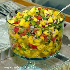 a glass bowl filled with pineapple salsa on top of a counter