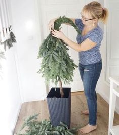 a woman is arranging a christmas tree on the floor