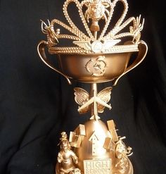 a gold trophy with an ornate crown on it's side and other decorations around the edges